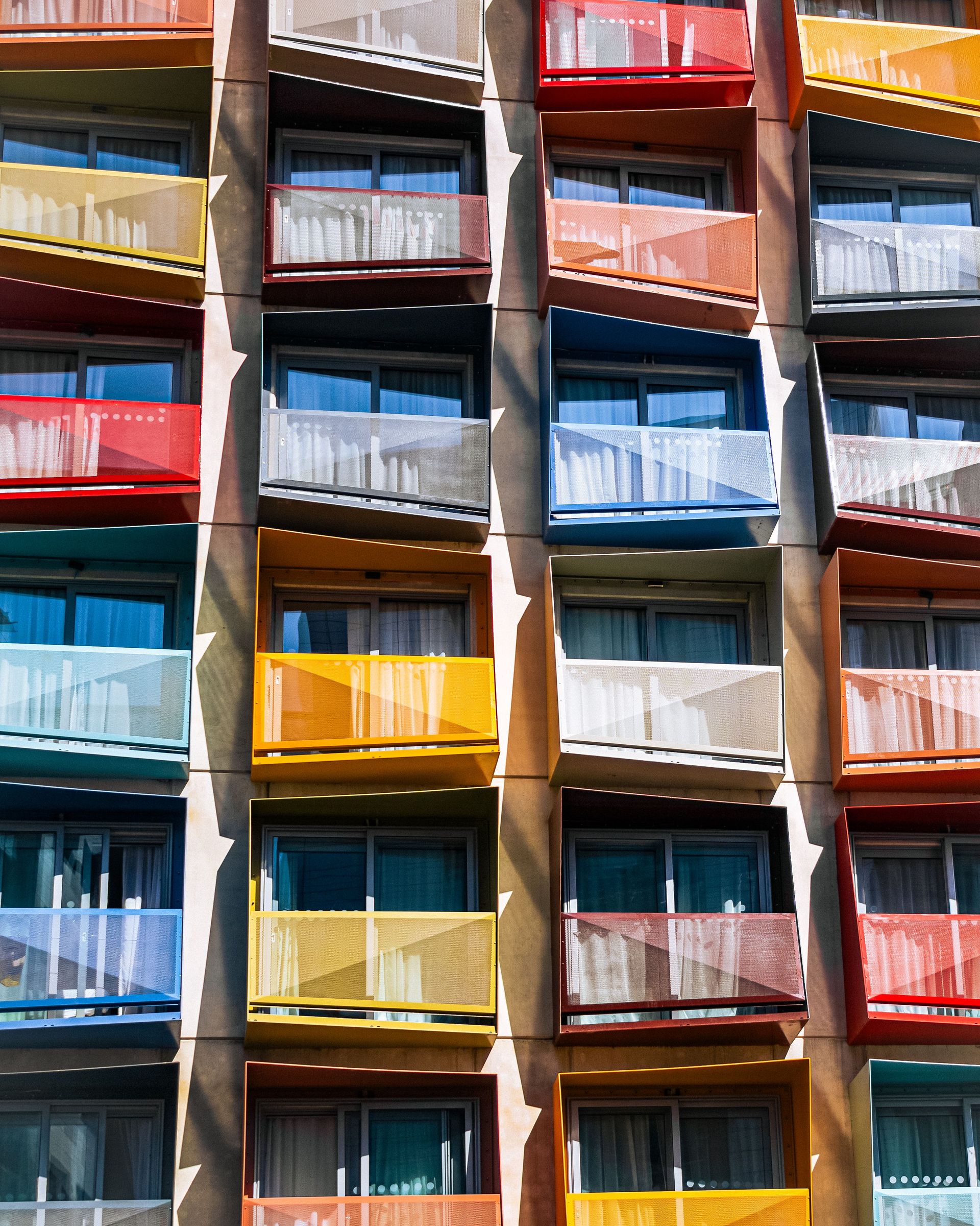 Vibrant facade of a modern apartment building featuring multicolored balconies in an urban setting.